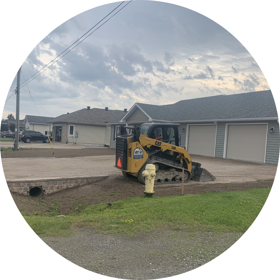 a skidsteer owned by Proficient Excavating in Sturgeon Falls, Ontario works to back grade a driveway with new gravel